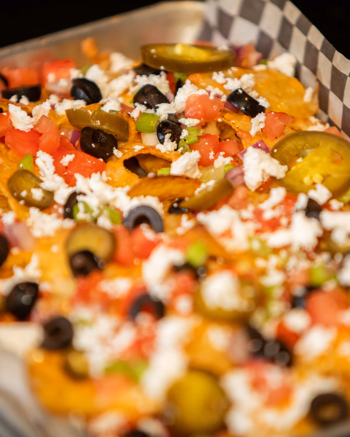 Mediterranean nachos topped with feta, olives, tomatoes, and jalapeños